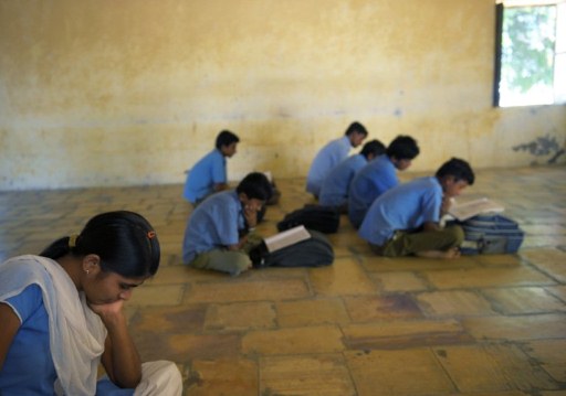 An Indian girl reading her book as she sits in a classroom full of boys. ©AFP