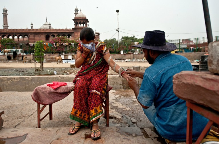  An Indian woman covers her face in pain as she is cut on her hand by Mohammed Iqbal. ©AFP