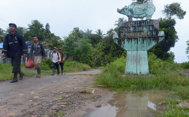 This picture taken on November 16, 2013 shows Indonesian rangers walking past a statue marking Ujung Kulon National Park in Indonesia's Banten province.