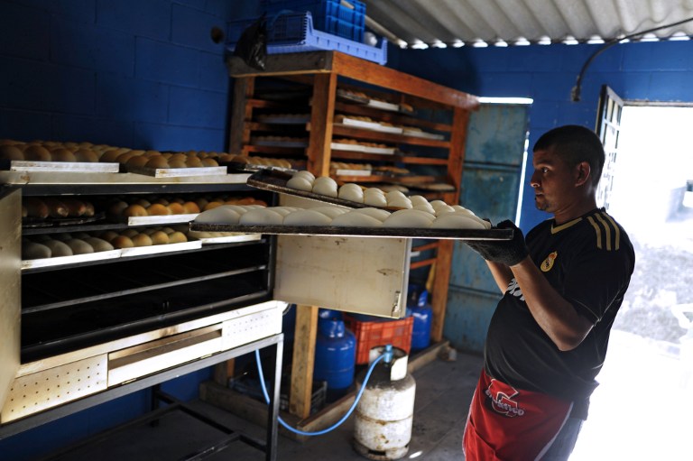 Jose Galdamez, of the 18th street gang, puts dough in the oven at a bakery. ©AFP