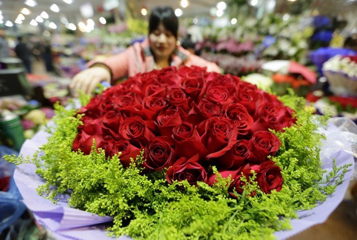 A florist decorating a bouquet of 99 red roses in Beijine, China. ©Reuters
