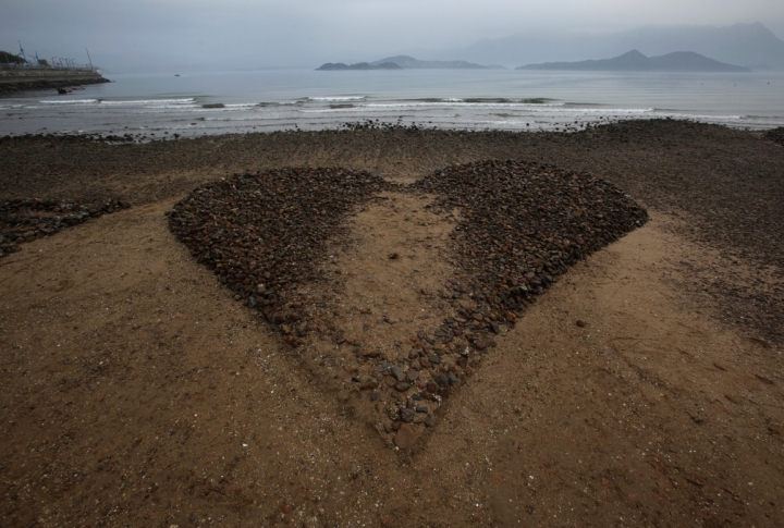 A heart-shaped sculpture made of sand and stone is seen during low tide at a beach in Hong Kong. ©REUTERS/Bobby Yip