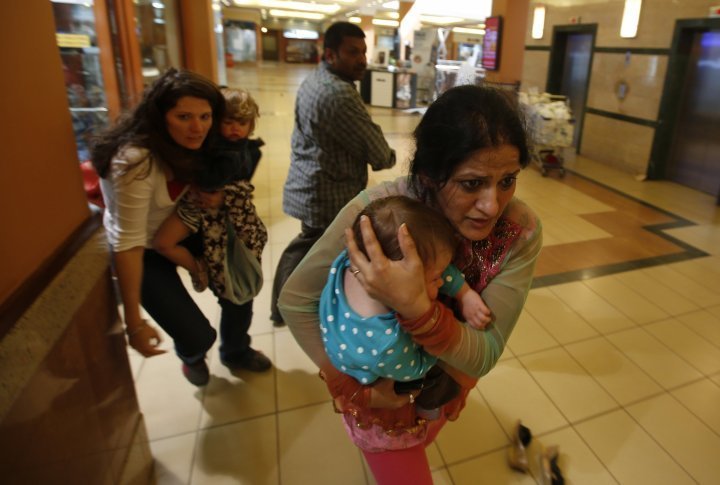 Women carrying children out of the trade center in Nairobi, September 21, 2013. ©REUTERS