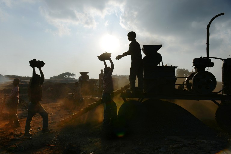 Indian children carry coal in baskets towards a coal crushing machine. ©AFP