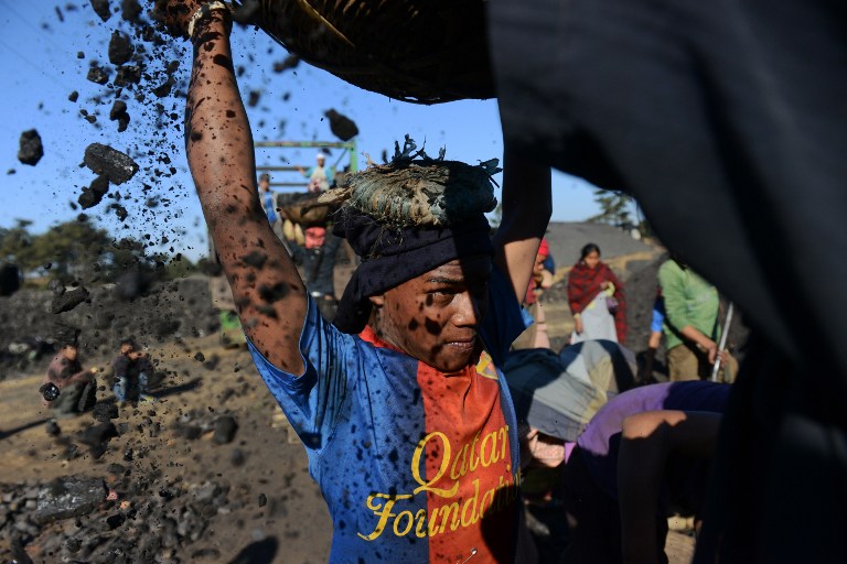 A young worker places a basket filled with coal. ©AFP