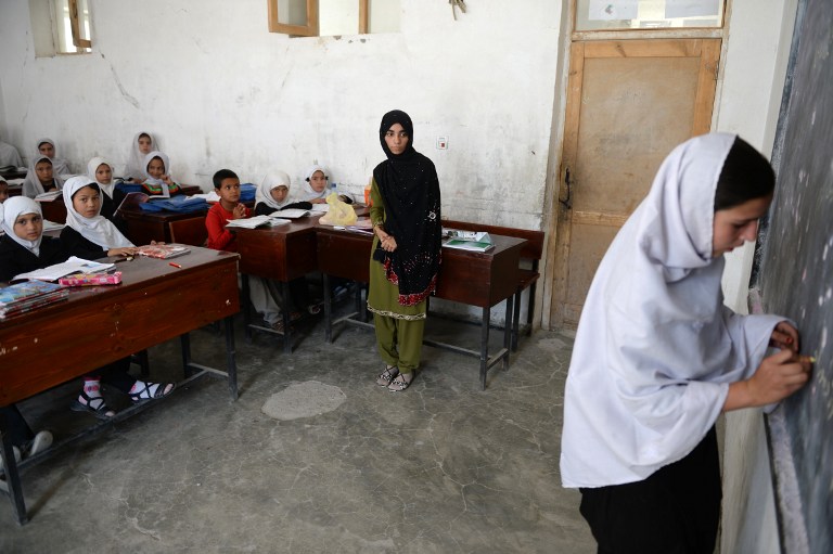 Shamsia Husseini (C) looks on as one of her students writes on the blackboard. ©AFP