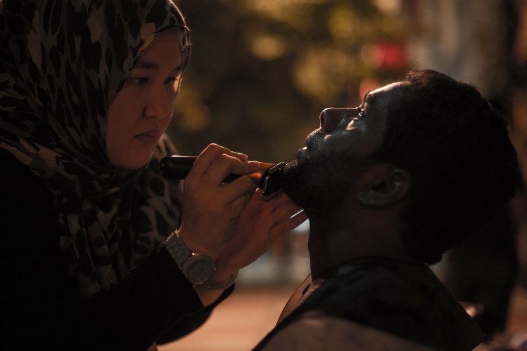 stylist Azmina Burhan (L) cutting the beard of a homeless man in downtown Kuala Lumpur.