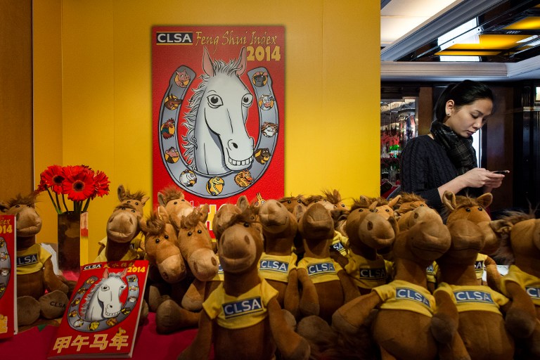 A woman uses a mobile phone next to horse soft toys during an event for the release of the annual CLSA Asia-Pacific Markets 