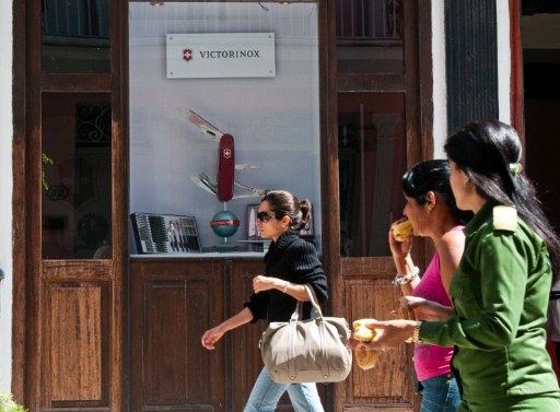 Cubans walk next to shop offering Victorinox Swiss brand products. ©AFP
