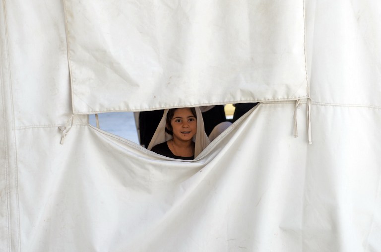 A schoolgirl looks out from their classroon in a tent at Mirwais Mena school. ©AFP