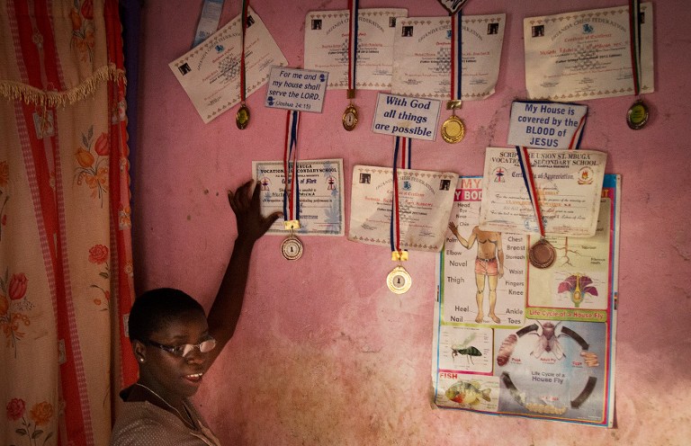 16 year old Phiona Mutesi poses with medals at her home in Kampala. ©AFP