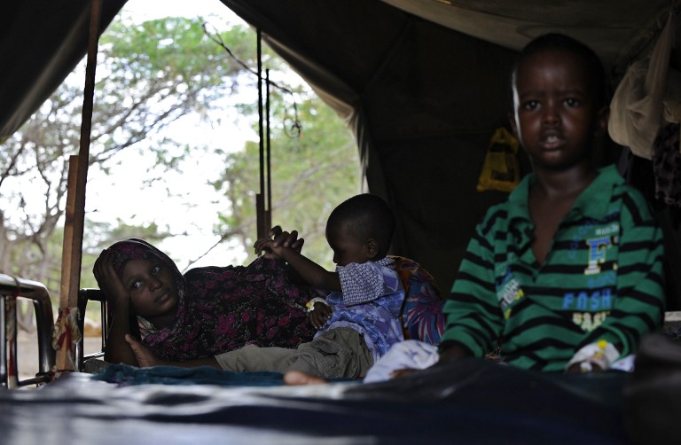A woman with her sick infant waits at a medical camp. ©AFP