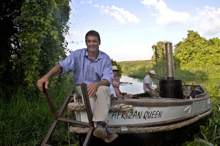 Cam McLeay, owner of the African Queen , sits on his boat with his colleagues on the shores of the River Nile in Jinja, Uganda, on December 21, 2013. 