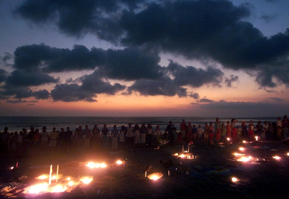 Westerners and Balinese join hands during a candlelight vigil for bomb victims at dusk October 14, 2002, on a beach near Kuta on the Indonesian resort island of Bali. ©Reuters