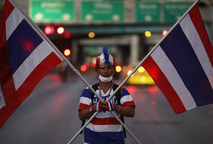 A protester holds Thai national flags in the center of Bangkok. ©Reuters
