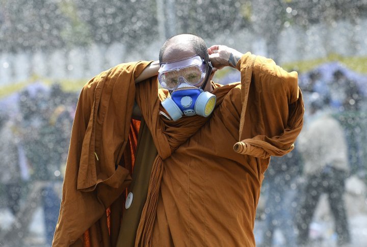 A Thai Buddhist puts on a gas mask, because the police is using water jets and tear gas against protesters. ©Reuters