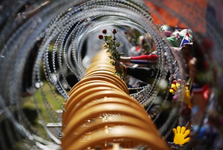 Demostrators are passing flowers to police through a barbed wire fence. ©Reuters