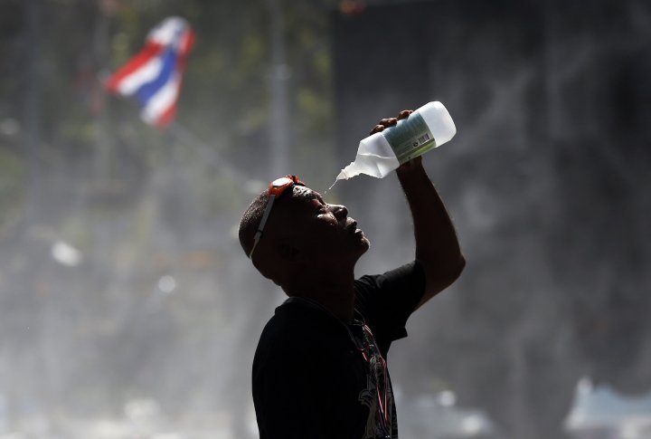 A demonstrator pours the water on his face, protecting his eyes from tear gas. ©Reuters
