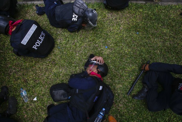 Policeman covers his face trying to protect himself from tear gas. ©Reuters