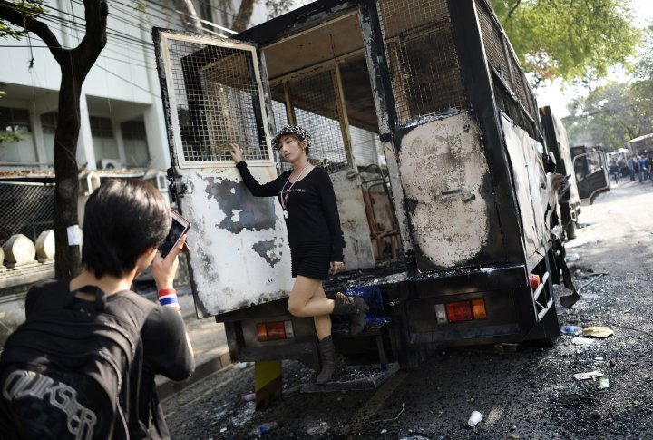 A girl posing with a burnt police vehicle. ©Reuters