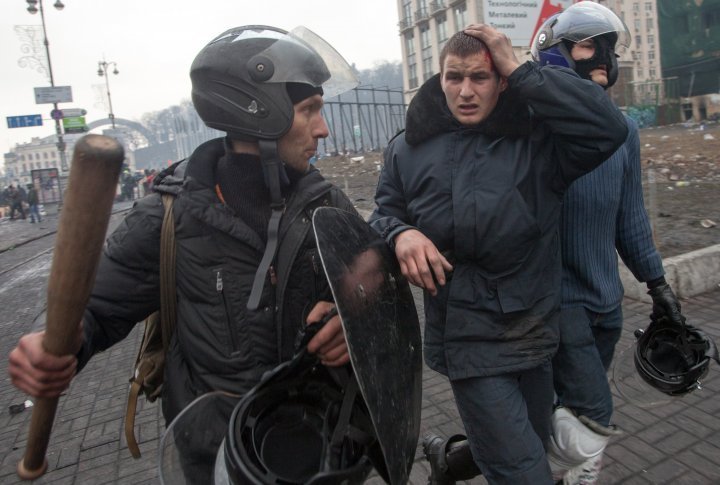 Anti-government protestors detain an injured policeman during clashes at the Maidan in Kiev. ©Reuters