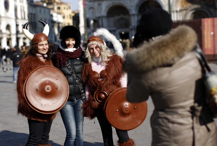 A tourist poses with revellers in Saint Mark's Square during the Venetian Carnival in Venice. ©REUTERS/Tony Gentile