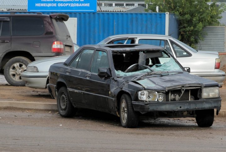 This car was damaged by an object that fell off the nearby restaurant building. Photo by  Danial Okassov©