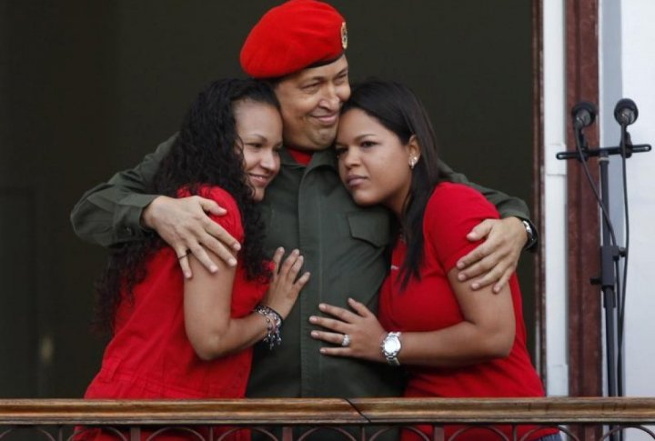 Venezuelan President Hugo Chavez hugs his daughters Rosa (L) and Maria while appearing to supporters on a balcony of Miraflores Palace soon after his return to the country from Cuba, where he underwent surgery and treatment for cancer. ©REUTERS/Carlos Garcia Rawlins