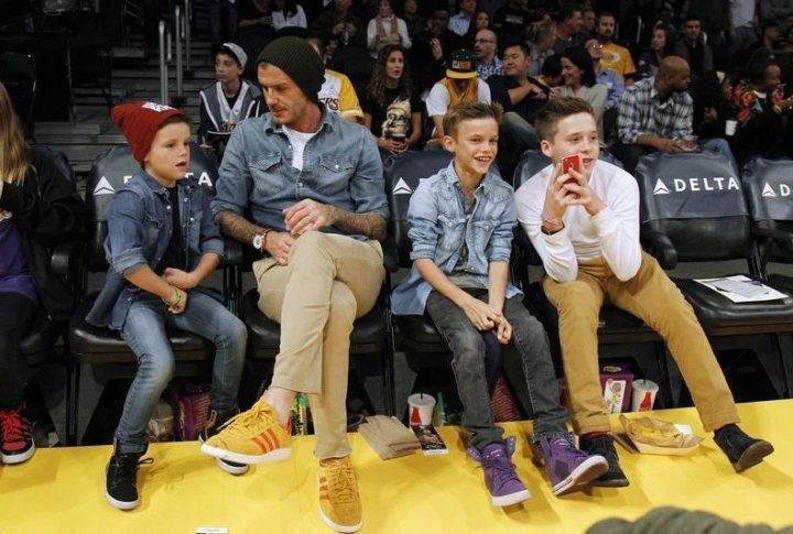 British soccer player David Beckham (2nd L) sits courtside with his sons Cruz (L), Romeo (2nd R) and Brooklyn (R). ©REUTERS/Danny Moloshok
