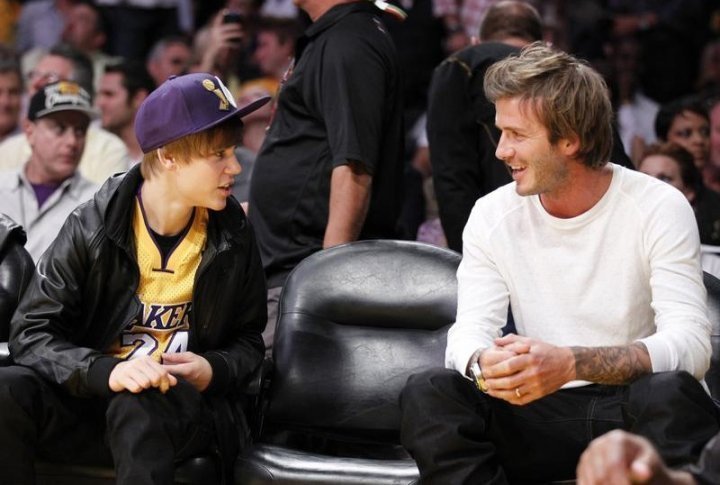 Singer Justin Bieber (L) of Canada chats to soccer player David Beckham during the NBA game. ©REUTERS/Lucy Nicholson