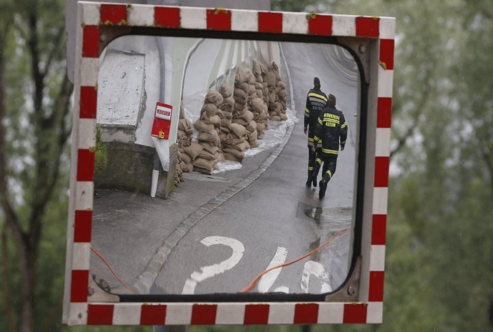 Members of the emergency services walking past sand bags protecting a building from flood water, are reflected in a traffic mirror in a street in the centre of the Austrian town of Melk. ©REUTERS