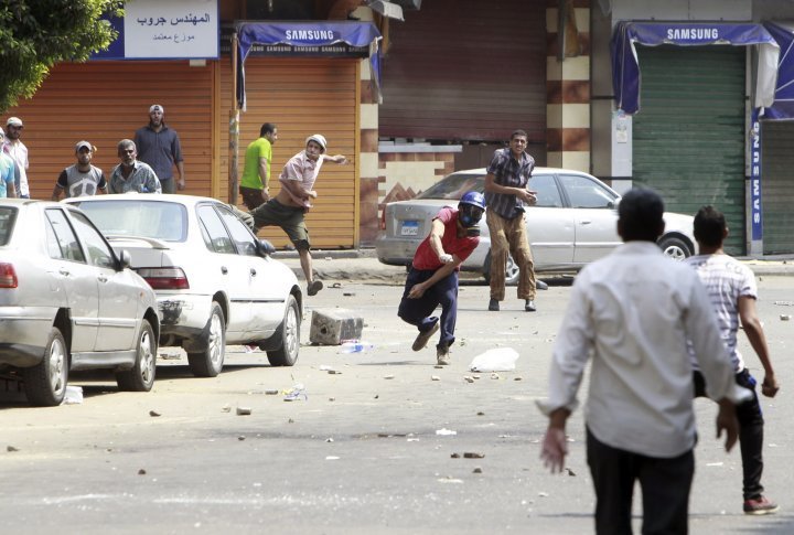 Supporters of ousted Egyptian President Mohamed Mursi (facing camera) throw stones towards local residents (foreground on R) during clashes in central Cairo August 13, 2013. ©REUTERS