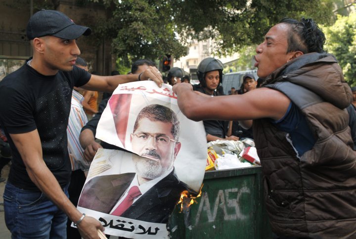 Local residents burn a poster of ousted President Mohamed Mursi, which was taken after Mursi supporters fled, during clashes in central Cairo August 13, 2013. ©REUTERS