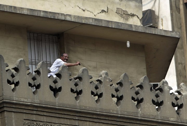 A supporter of the new military-installed government throws bottles from the Ministry of Religious Endowments building, at supporters of ousted Egyptian President Mohamed Mursi, during clashes in central Cairo August 13, 2013. ©REUTERS