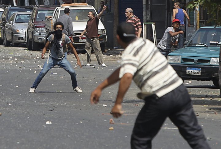 A local resident (rear L, facing camera) throws stones towards supporters of ousted President Mohamed Mursi during clashes in central Cairo August 13, 2013. ©REUTERS