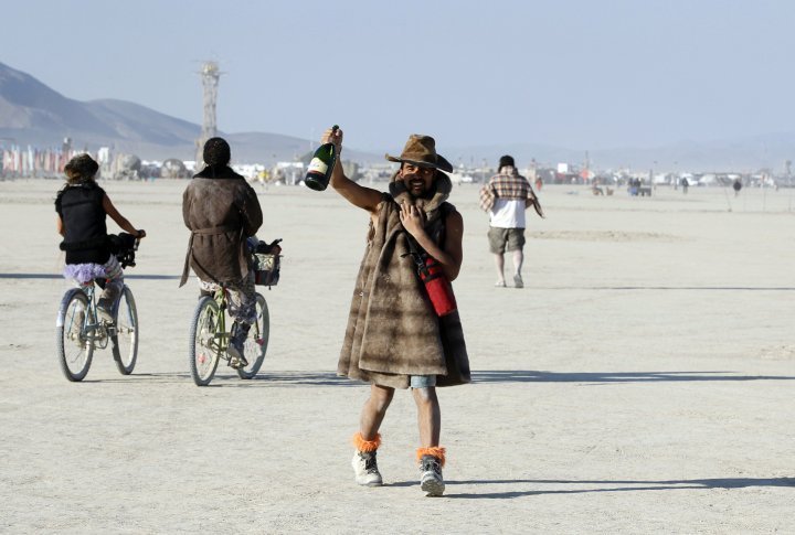 A Burning Man participant toasts the sunrise with a bottle of champagne. ©REUTERS