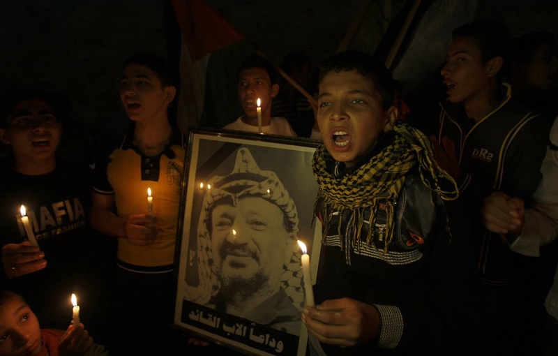 Palestinians hold candles and a poster depicting late Palestinian president Arafat. ©REUTERS