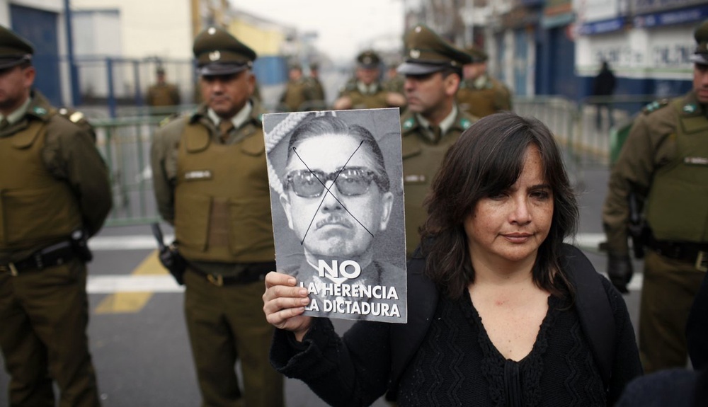 A human rights activist holds up a portrait of late former Chilean dictator Augusto Pinochet. ©REUTERS