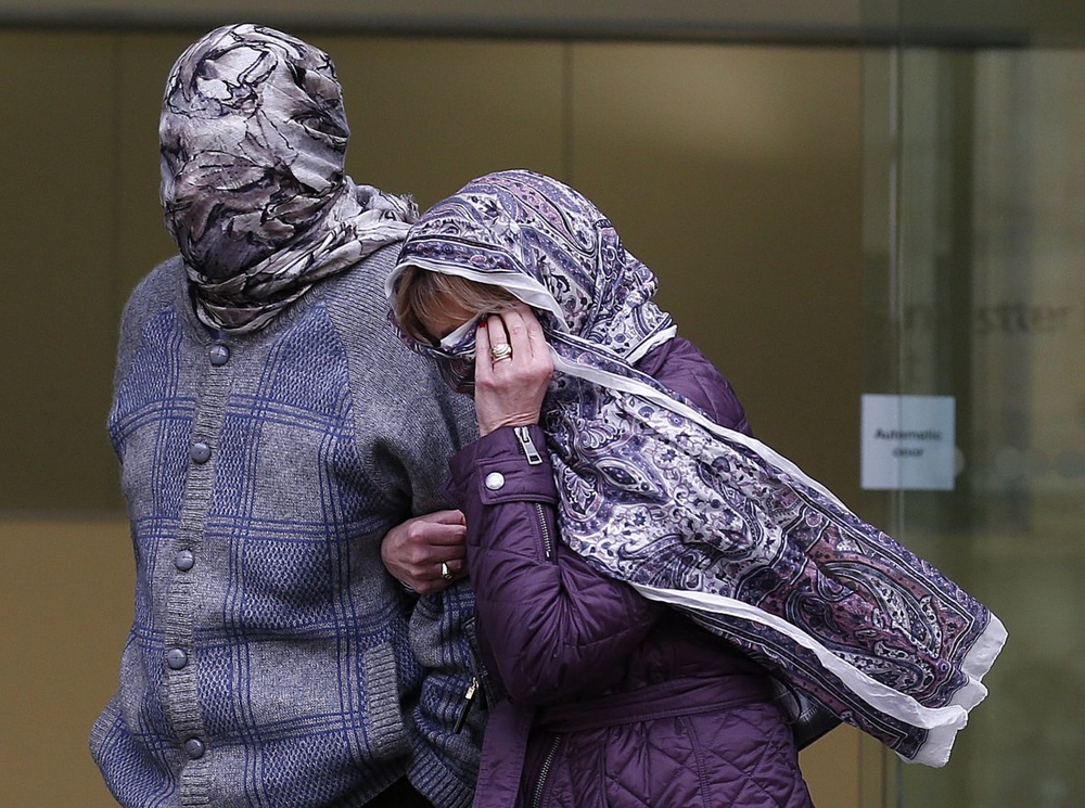 Domenico Rancadore (L) and his wife Anne Skinner cover their faces. ©Reuters/Olivia Harris