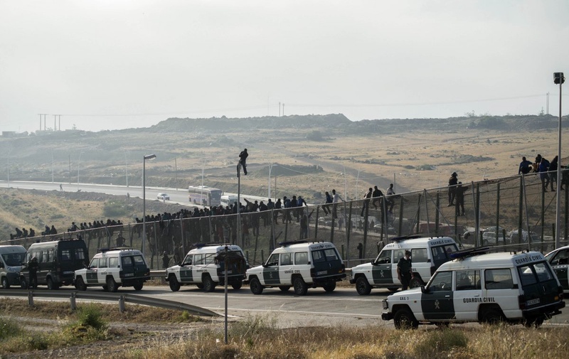 Vehicles from the Spanish Civil Guard are seen positioned at a border fence covered in razor wire as African migrants try to climb it. ©Reuters/Jesus Blasco de Avellaneda 