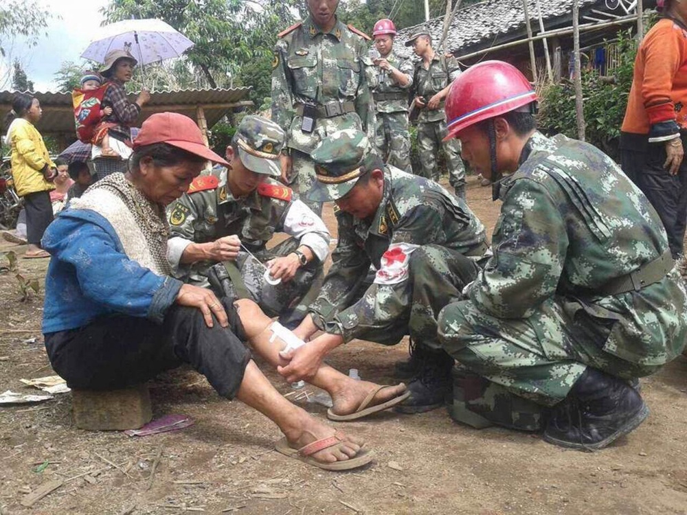 Paramilitary policemen treat an injured woman after a 6.1 magnitude earthquake hit Yingjiang county, Yunan province. ©Reuters/Stringer 