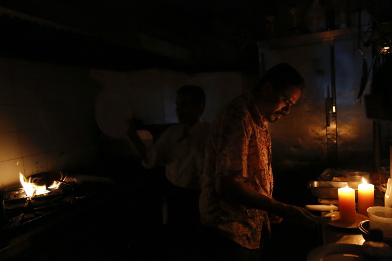 Restaurant workers try to finish up orders in the kitchen during a blackout in Caracas. ©Reuters/Carlos Garcia Rawlins