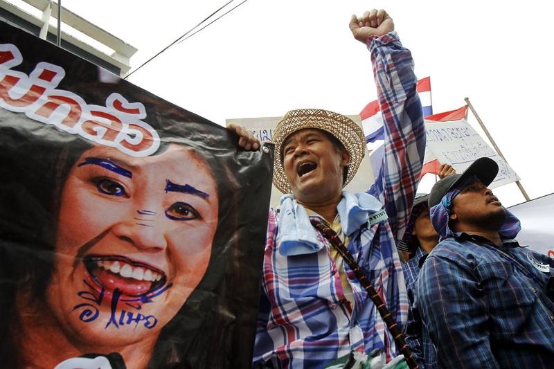 Farmers hold a defaced poster of Thai Prime Minister Yingluck Shinawatra. ©Reuters/Chaiwat Subprasom