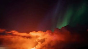 Northern lights appear against the backdrop of a volcanic eruption in Iceland